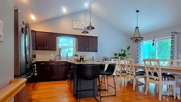 Una cocina amplia con armarios de madera oscura, una isla grande con taburetes de bar e iluminación colgante.