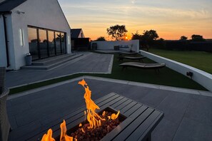 A modern outdoor patio with a fire feature, seating, and a view of the sunset. - Jeannies retreat at little lake fb (Ballymoney)