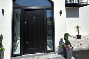A black double door with a glass panel, a white wall, and a balcony with a black railing. - Jeannies retreat at little lake fb (Ballymoney)