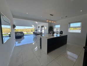 A modern kitchen with a large island, a dining area with a sofa, and a view of the outdoors. - Jeannies retreat at little lake fb (Ballymoney)