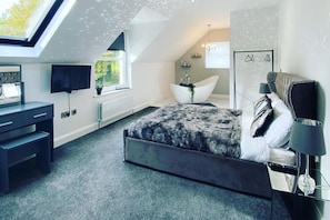 A modern bedroom with a skylight, a large bed, a desk, and a bathtub. - Jeannies retreat at little lake fb (Ballymoney)