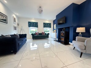 A living room with a sofa, a chair, a fireplace, and a TV mounted on the wall. - Jeannies retreat at little lake fb (Ballymoney)