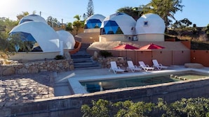A resort with dome-shaped accommodations, a swimming pool, and a stone pathway.