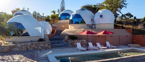 Un resort con alojamientos de forma abovedada, piscina y un sendero de piedra.