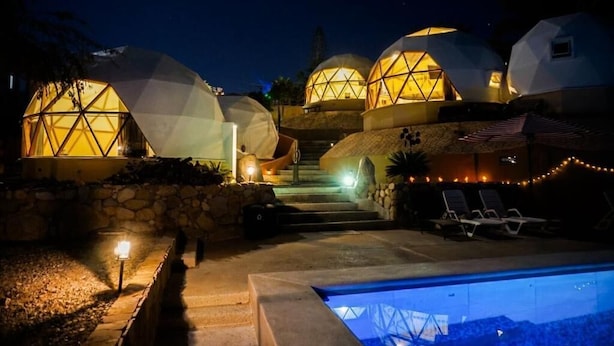 A series of geodesic dome structures with a swimming pool and lounge chairs in the foreground.