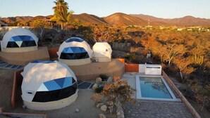 Geodesic dome structures with a pool and desert landscape.