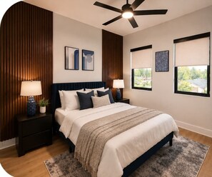 Une chambre à coucher avec un lit, deux tables de chevet, un ventilateur de plafond et une vue sur l’extérieur.