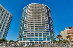 A multi-story hotel with a curved facade, balconies, and a pool area with sun loungers. - 2-bedroom condo in soothing Myrtle Beach/ Modern Decor. Stunning View-14th Flr (Myrtle Beach)