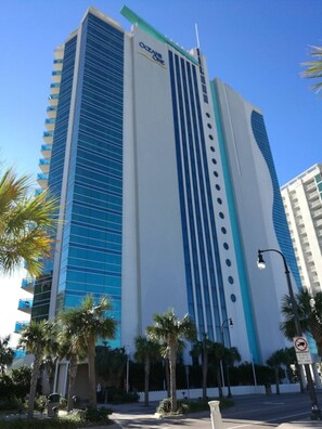 A tall hotel with a distinctive blue and white facade, palm trees in the foreground, and a clear blue sky. - 2-bedroom condo in soothing Myrtle Beach/ Modern Decor. Stunning View-14th Flr (Myrtle Beach)