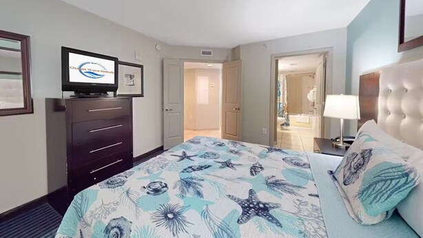 Ein Hotelzimmer mit Bett, Fernseher, Kommode und einem durchgegangenen Tür erkennbaren Badezimmer.