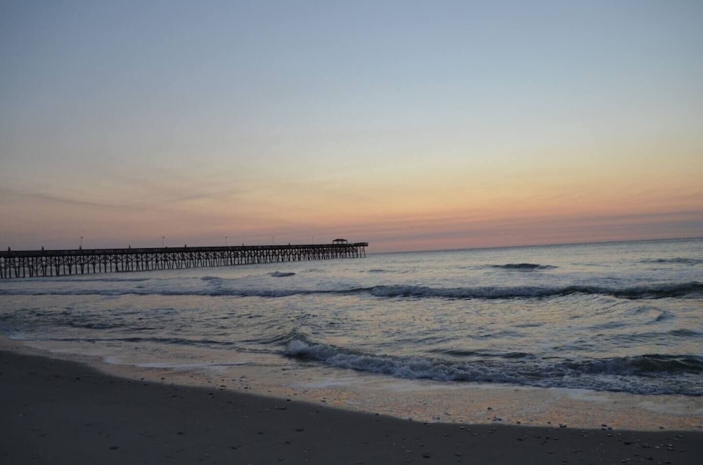 A beach with a pier extending into the water.
