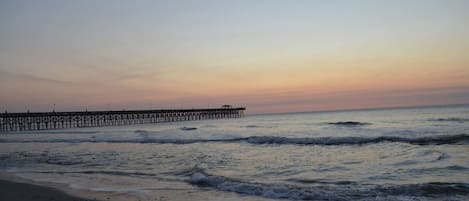 A beach with a pier extending into the water.