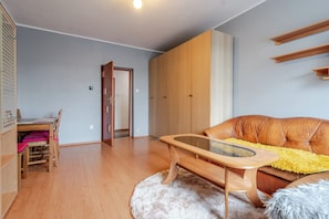 Ein Wohnzimmer mit Couchtisch aus Holz, einem braunen Ledersofa, einem flauschigen weißen Teppich und Holzregalen.