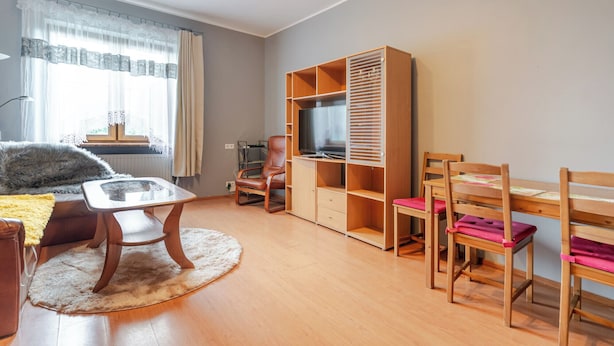 Une pièce bien éclairée, avec un bureau en bois, des chaises, un téléviseur et une grande armoire.