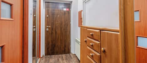 A hallway with wooden doors, a radiator, and a wooden cabinet with drawers.