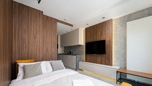 A modern bedroom with a bed, bedside table, and a TV mounted on the wall. - National Stadium Signature Studio (Warszawa)