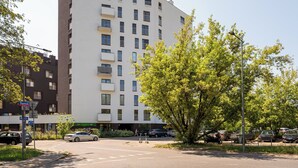 A multi-story building with a flat roof, several balconies, and a parking lot with cars. - National Stadium Signature Studio (Warszawa)