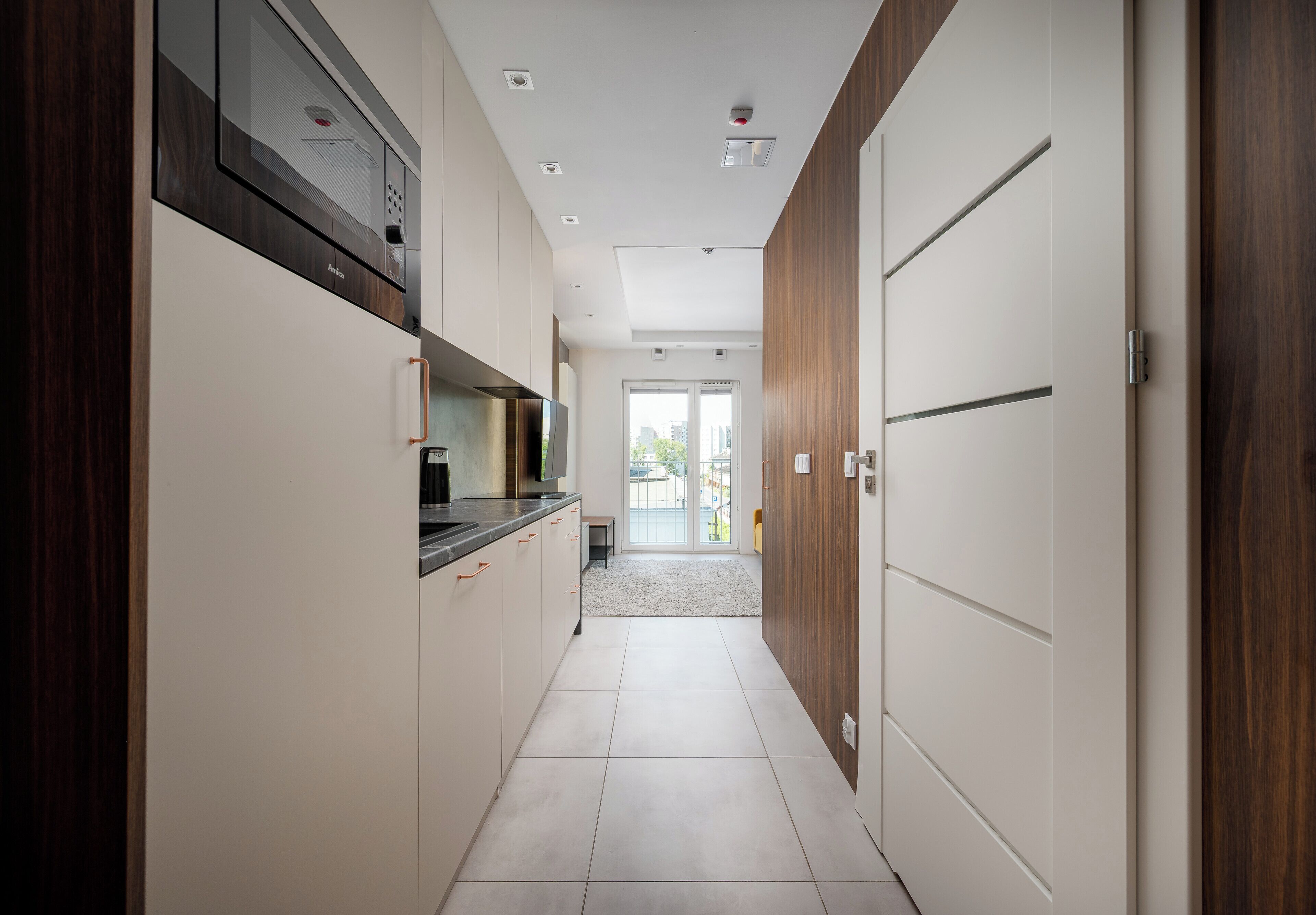 A modern kitchen with a built-in oven, a microwave, and a coffee machine.