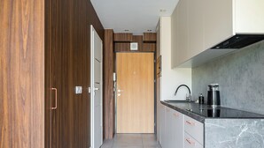 A modern kitchen with a wooden door, grey cabinets, and a black countertop. - National Stadium Signature Studio (Warszawa)