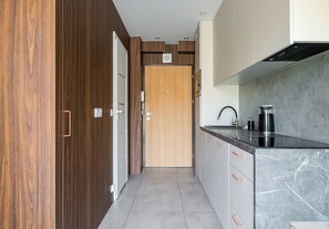 Eine moderne Küche mit Holztür, grauen Schränken und einer schwarzen Arbeitsplatte.