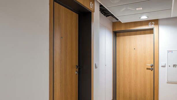 A hallway with two wooden doors, each marked with a number. - National Stadium Signature Studio (Warszawa)