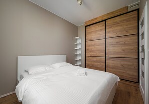 Ein Schlafzimmer mit einem Bett, einem Holzschrank und einem weißen Regal.