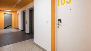 Käytävä, jossa on ovi, jonka yläpuolella on kyltti, jossa lukee ’105’, ja portaat, jotka johtavat toiseen huoneeseen.