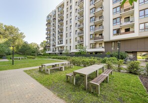 A multi-story residential building with balconies, a paved outdoor area with benches, and a grassy courtyard. - Pieskowa Skała 15 Prestige Apartment (Warszawa)
