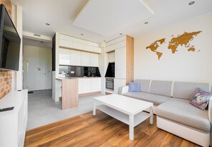 A modern living space with a kitchen, a sofa, and a coffee table. - Pieskowa Skała 15 Prestige Apartment (Warszawa)