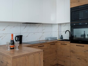 Eine moderne Küche mit integriertem Mikrowellenherd, Backofen und einer Holzarbeitsplatte.