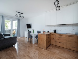Eine moderne Küche mit Holzschränken, einem Esstisch und einer Couch in einem hellen Wohnbereich mit einer Glastür.
