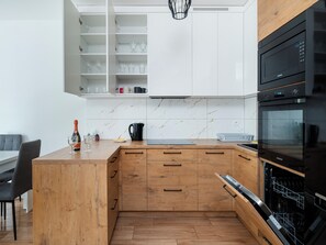 Una cocina moderna con armarios blancos, encimera de madera y lavavajillas integrado.