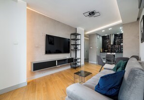 A modern living room with a flat-screen TV, built-in shelves, a sofa, and a coffee table. - Wronia Business Deluxe Residence (Warszawa)