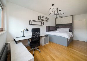 A modern bedroom with a bed, desk, chair, and pendant lights. - Wronia Business Deluxe Residence (Warszawa)