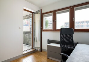 Ein Zimmer mit einer Schiebetür, einem Heizkörper, einem Schreibtisch mit Stuhl und einem Fenster mit Jalousien.