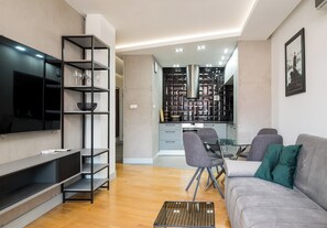 Ein modernes Wohnzimmer mit Flachbildfernseher, einer Couch und einem Essbereich mit Stühlen.