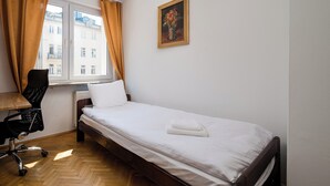 A bedroom with a bed, a chair, a radiator, and a window with curtains. - Złota Heart of Warsaw Apartment (Warszawa)