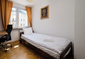 A bedroom with a bed, a chair, a radiator, and a window with curtains. - Złota Heart of Warsaw Apartment (Warszawa)
