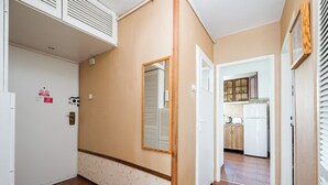 A hallway with a white door, a mirror, and a kitchen area visible through an open door. - Złota Heart of Warsaw Apartment (Warszawa)