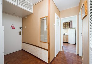 A hallway with a white door, a mirror, and a kitchen area visible through an open door. - Złota Heart of Warsaw Apartment (Warszawa)