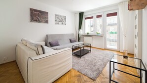 A modern living room with a sofa, a glass coffee table, and a view of the city through large windows. - Złota Heart of Warsaw Apartment (Warszawa)