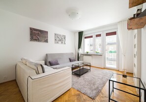 A modern living room with a sofa, a glass coffee table, and a view of the city through large windows. - Złota Heart of Warsaw Apartment (Warszawa)