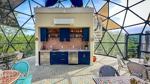 Une cuisine moderne dotée d’un plafond en verre aux motifs géométriques, entourée d’un espace extérieur aménagé avec des carreaux décoratifs.