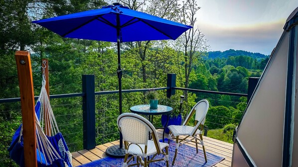 Une terrasse avec deux fauteuils en osier, une petite table ronde et un parasol bleu.