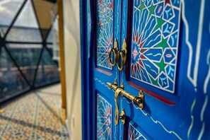 Une porte bleue ornée de motifs géométriques complexes et dotée de ferrures en laiton.