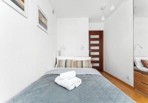 Une chambre à coucher avec un lit, une porte en bois, une table de chevet et une lampe fixée au mur.