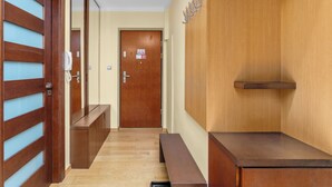 Un pasillo con puertas de madera, un banco, una recepción y un estante en la pared.