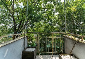 A concrete staircase with metal railings leading to a covered area surrounded by trees. - Dembowskiego Cosy Nest Apartment (Kraków)