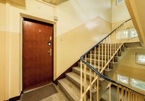 A wooden door with a number plate, a staircase with metal railings, and a carpeted landing. - Dembowskiego Cosy Nest Apartment (Kraków)