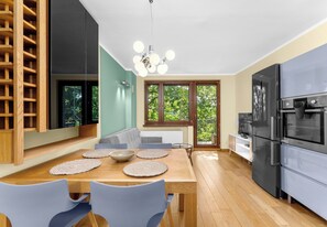 Eine moderne Küche mit Essbereich, einem großen Kühlschrank und Blick auf Grünflächen.